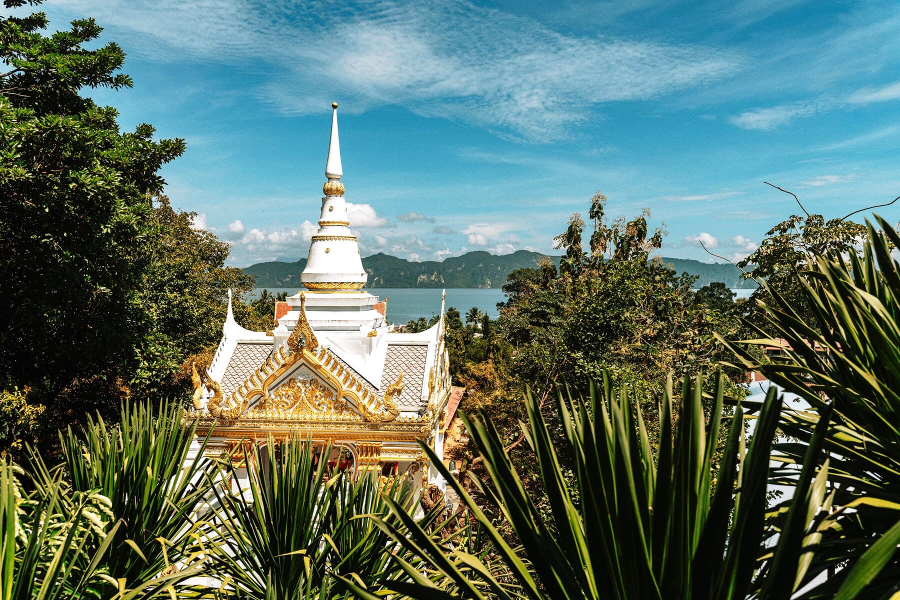 Golden Buddhist temple with sea and cliffs behind